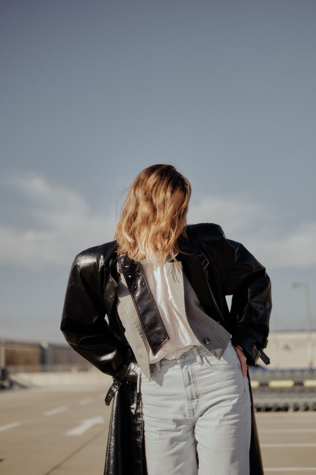 A fashionable woman in a leather jacket and light-wash jeans on a rooftop — wash and styling