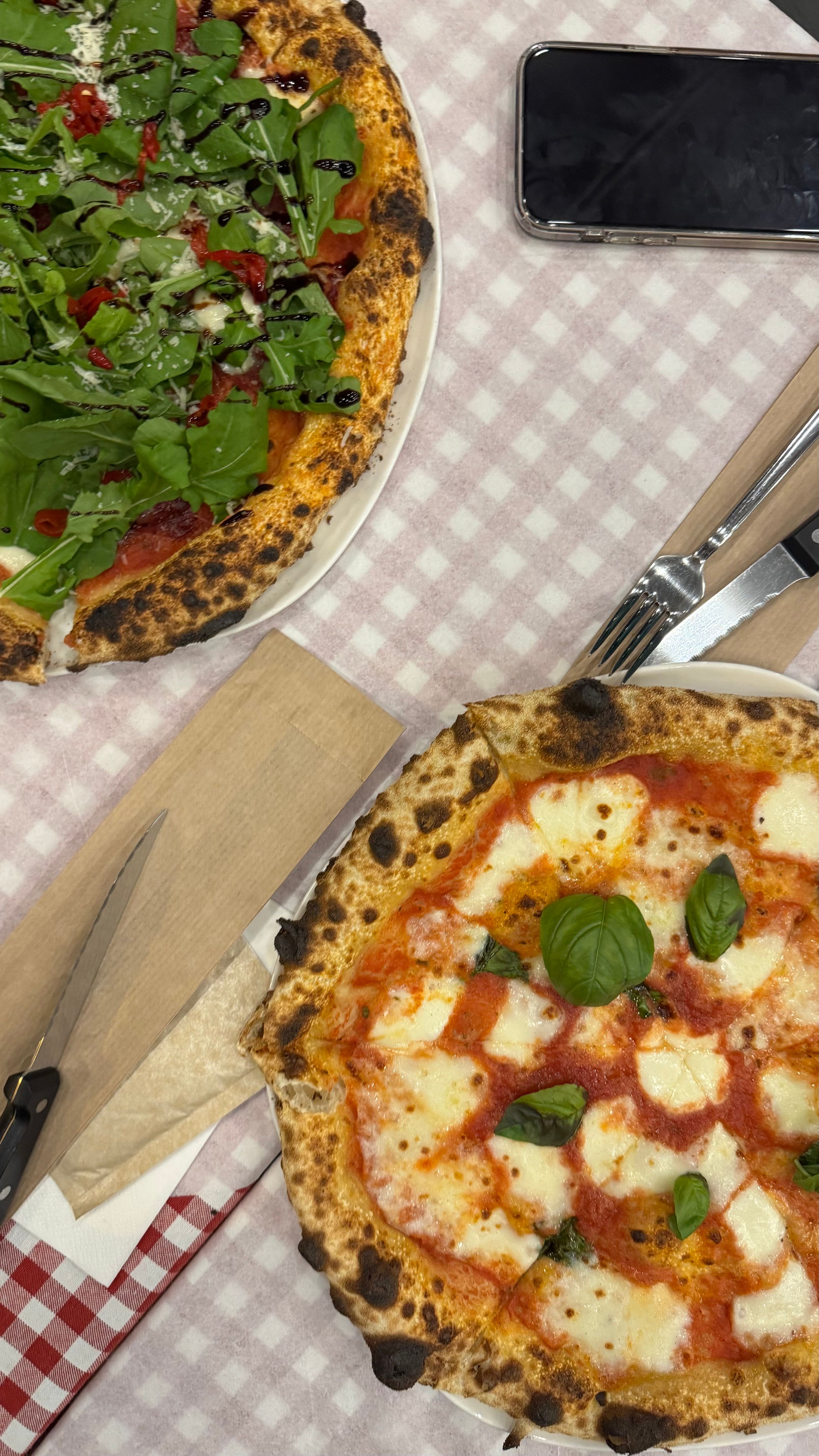 Ilmainen Kaksi maukasta napolilaista pizzaa ruudullisella pöytäliinalla, täydellinen italialainen ruokailu. Kuvapankkikuva