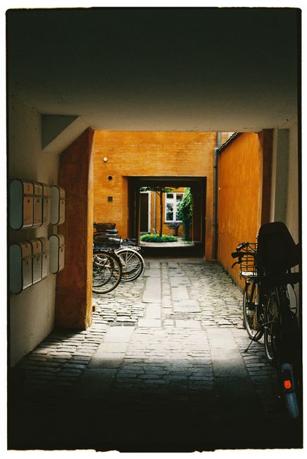 Serene urban alley with bicycles and vibrant yellow walls under daylight.
