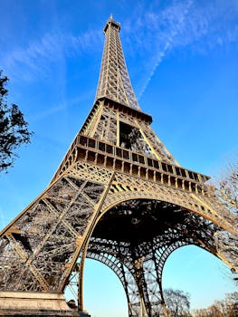Upward view of the iconic Eiffel Tower on a sunny Paris day.