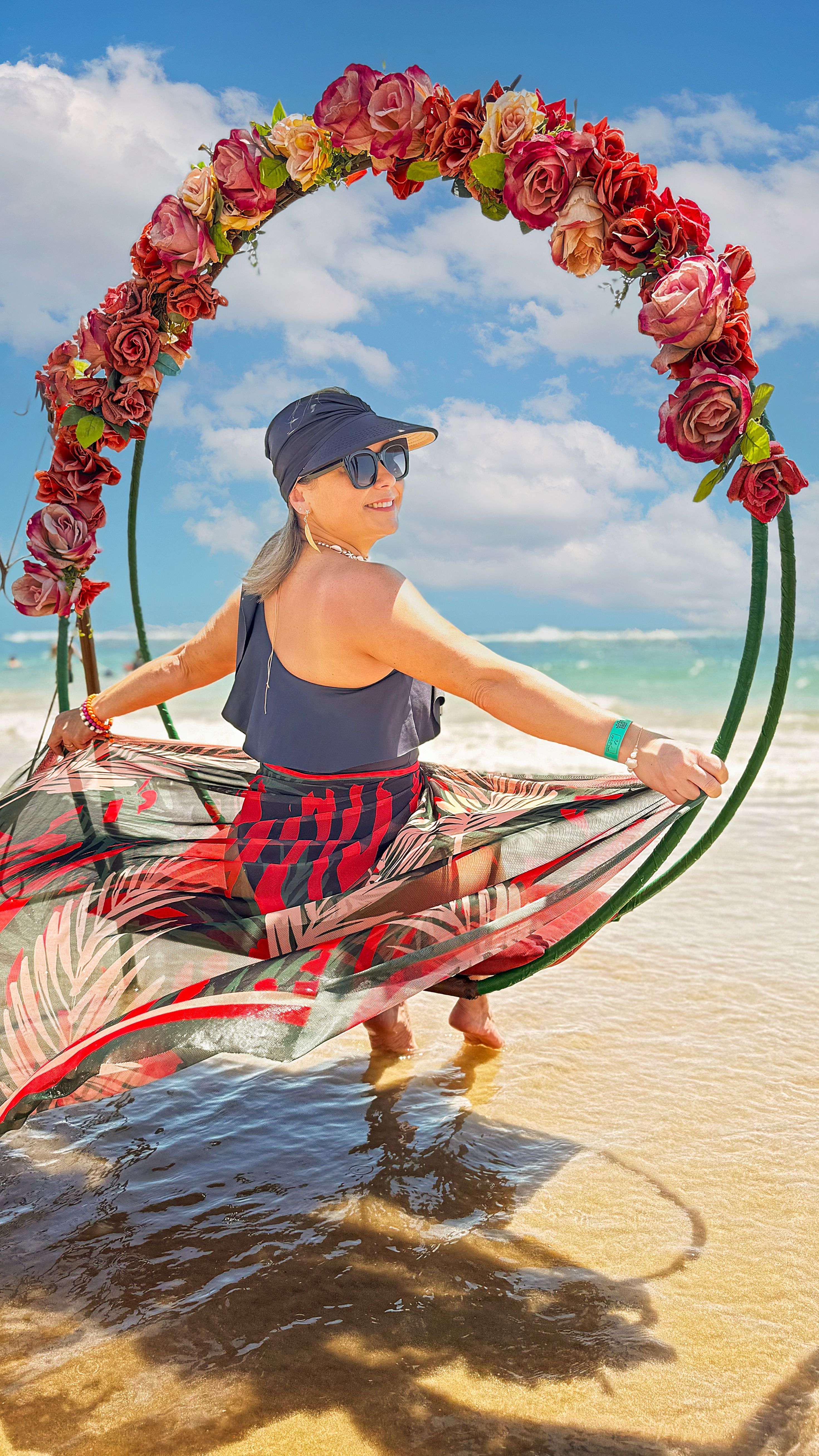 Mulher sorridente em um balanço floral aproveitando um dia ensolarado na praia.
