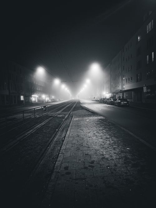 Free A foggy night street scene in Munich, Germany, with illuminated streetlights and a moody atmosphere. Stock Photo