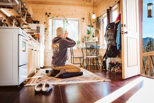 A person meditates in a cozy wooden cabin with mountain views in Colorado.
