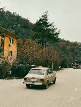Classic car driving on a quiet autumn road, rural and peaceful setting.