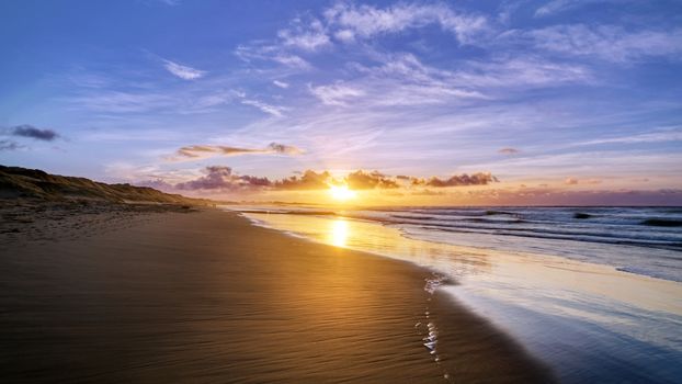 A breathtaking sunset over a tranquil beach, with vibrant sky and serene ocean waves.