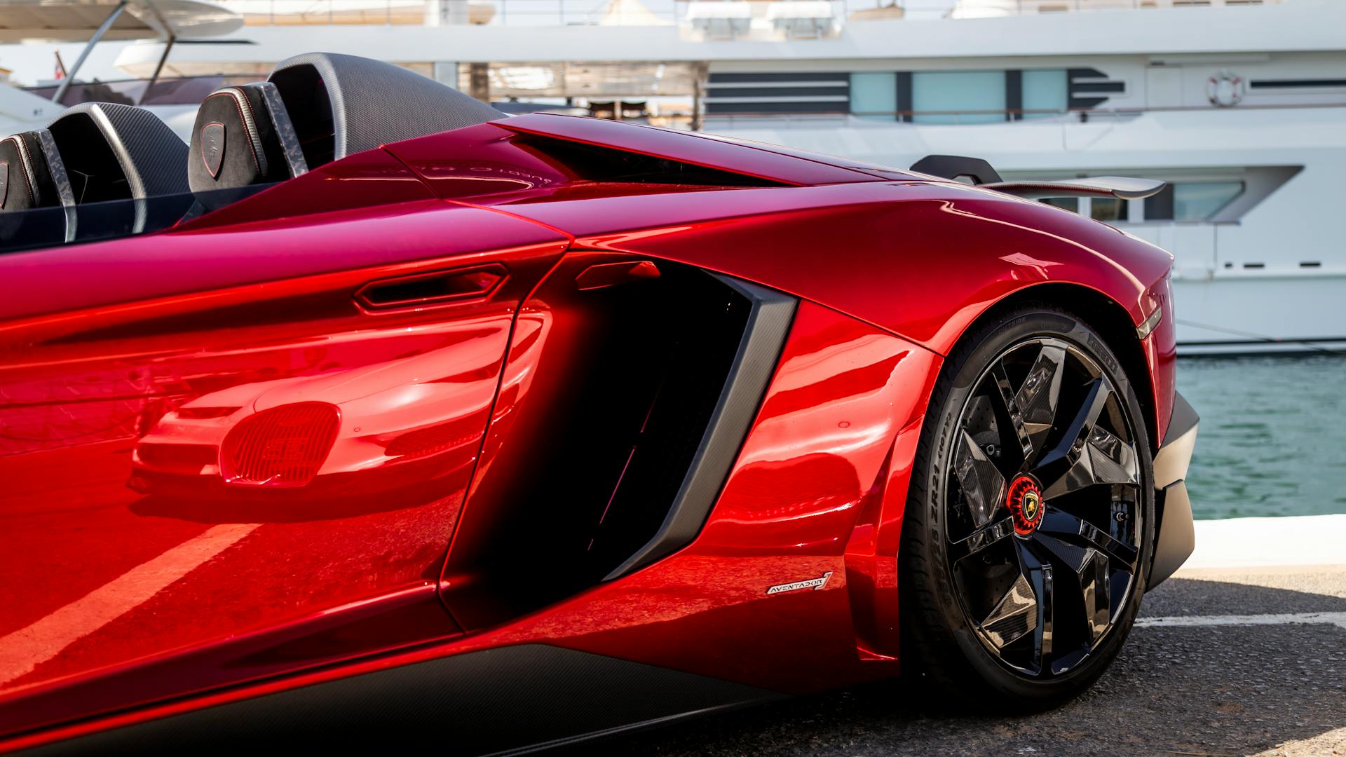 Luxury red supercar parked by the marina in Marbella, showcasing elegance and style at sunset.