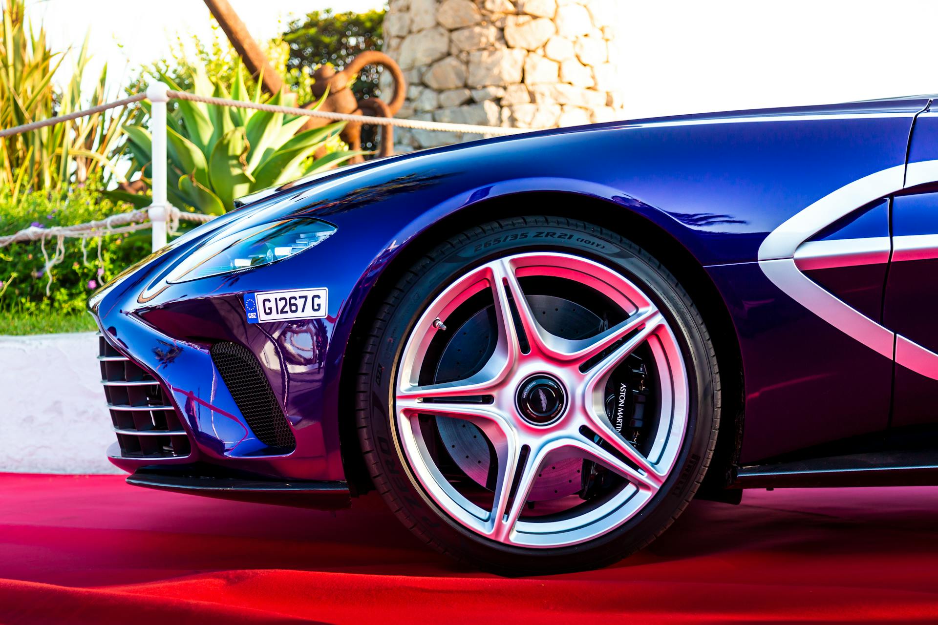 Close-up shot of a luxury sports car wheel on red carpet during outdoor event.