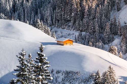 Free A cozy wooden cabin surrounded by snow-covered Alps in Zillertal, Austria. Stock Photo