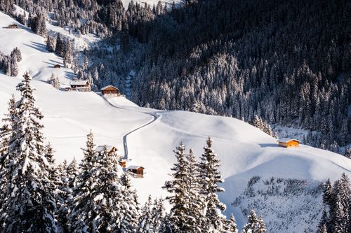 Free Idyllic snowy scene in Zillertal, Austria featuring wooden cabins and forested mountains. Stock Photo