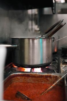 A pot of pasta sauce simmers on a professional kitchen stove, enhancing its rich flavor.