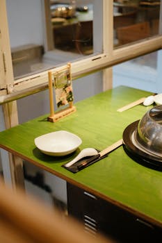 A neatly set table in a cozy restaurant with a vibrant green surface and cutlery arranged.