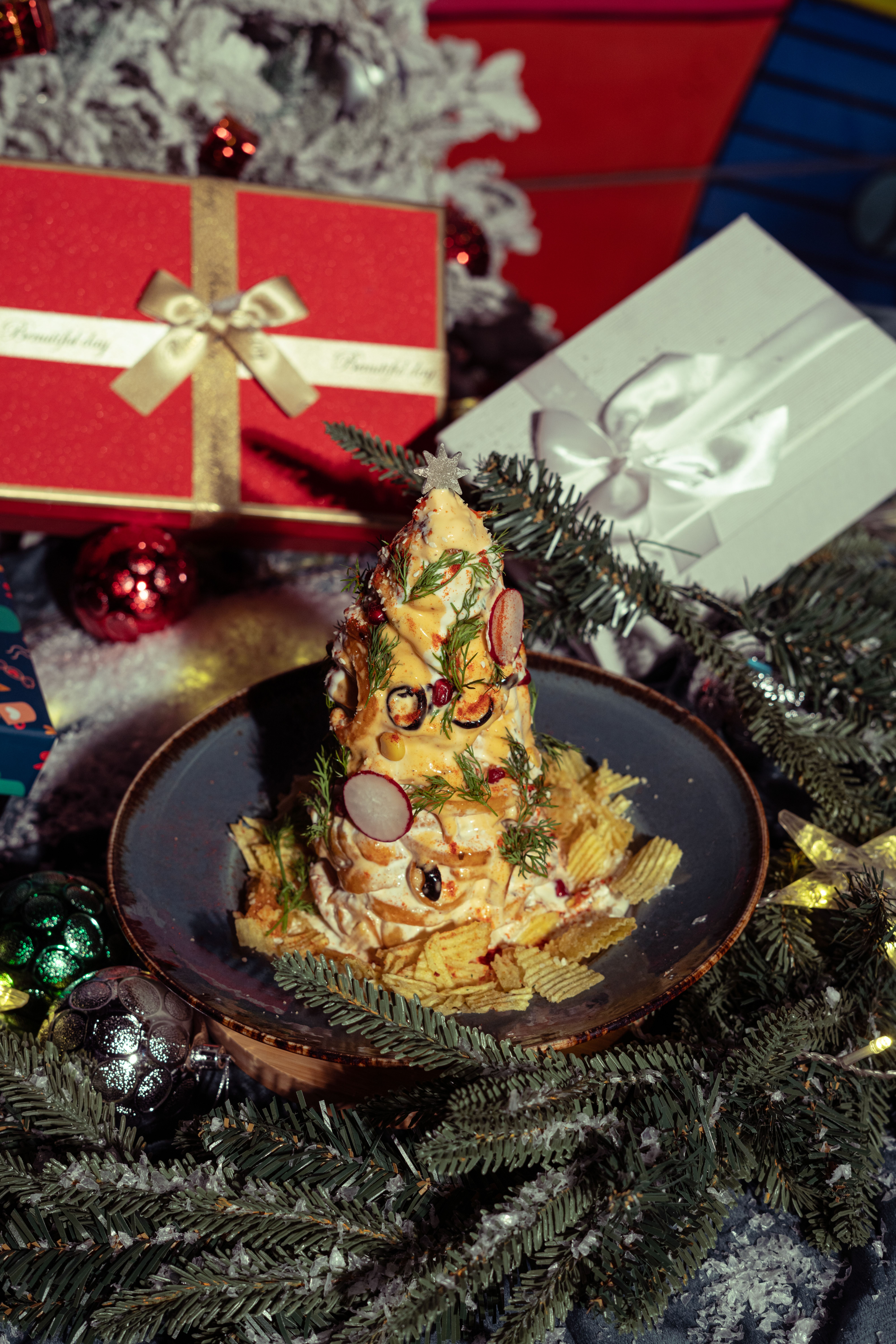 A creative Christmas cheese platter shaped like a tree surrounded by gifts.
