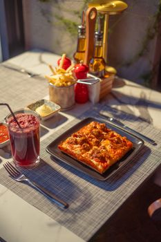 Delicious square pizza with drink on elegant table, perfect for dining themes.