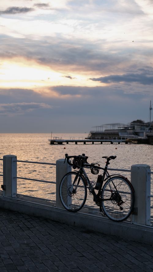 Free A bicycle rests along a calm seaside promenade during a peaceful sunset. Stock Photo