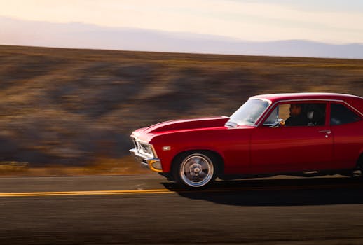 A classic red car speeding along an open road during sunset, capturing the essence of travel and freedom.
