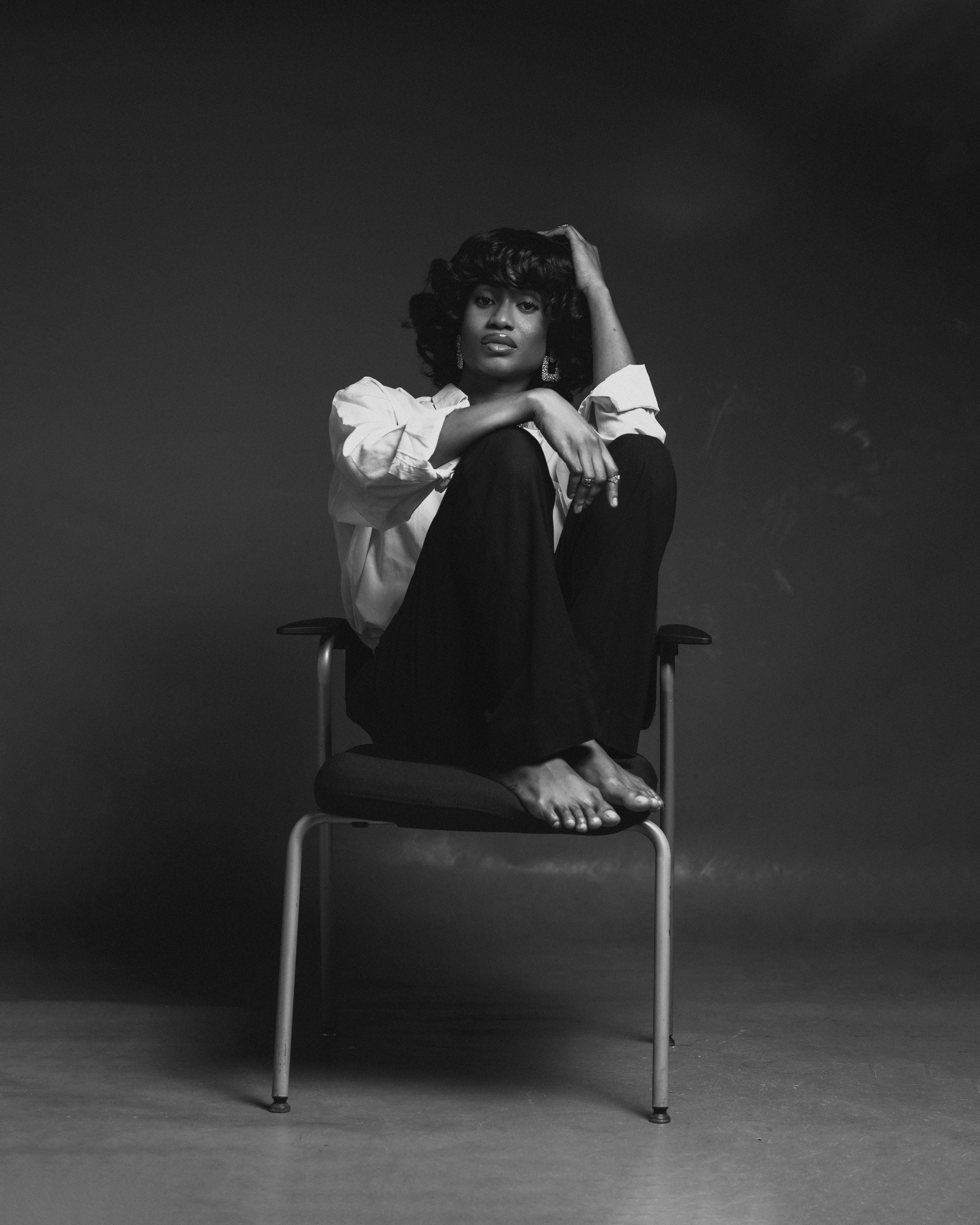Artistic black and white portrait of an adult sitting on a chair.