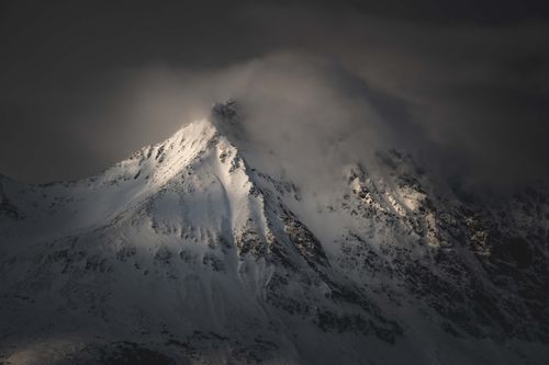 Free A misty snow-covered mountain peak with dramatic lighting in a wintry evening landscape. Stock Photo