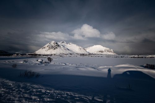 Free A stunning winter landscape featuring snow-covered mountains and a shadow cast on the snow. Stock Photo