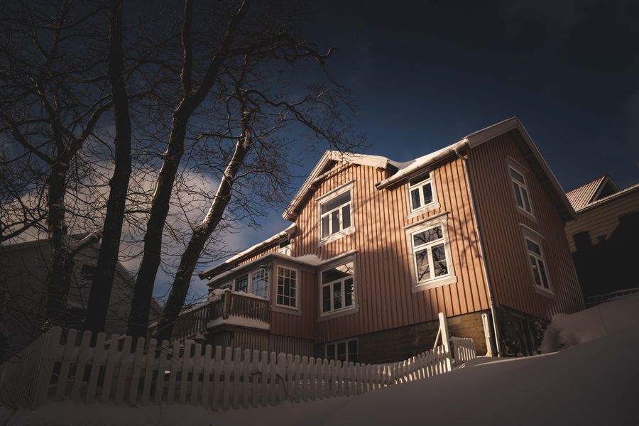 Idyllic wooden house with snow and dramatic lighting under a clear winter sky.