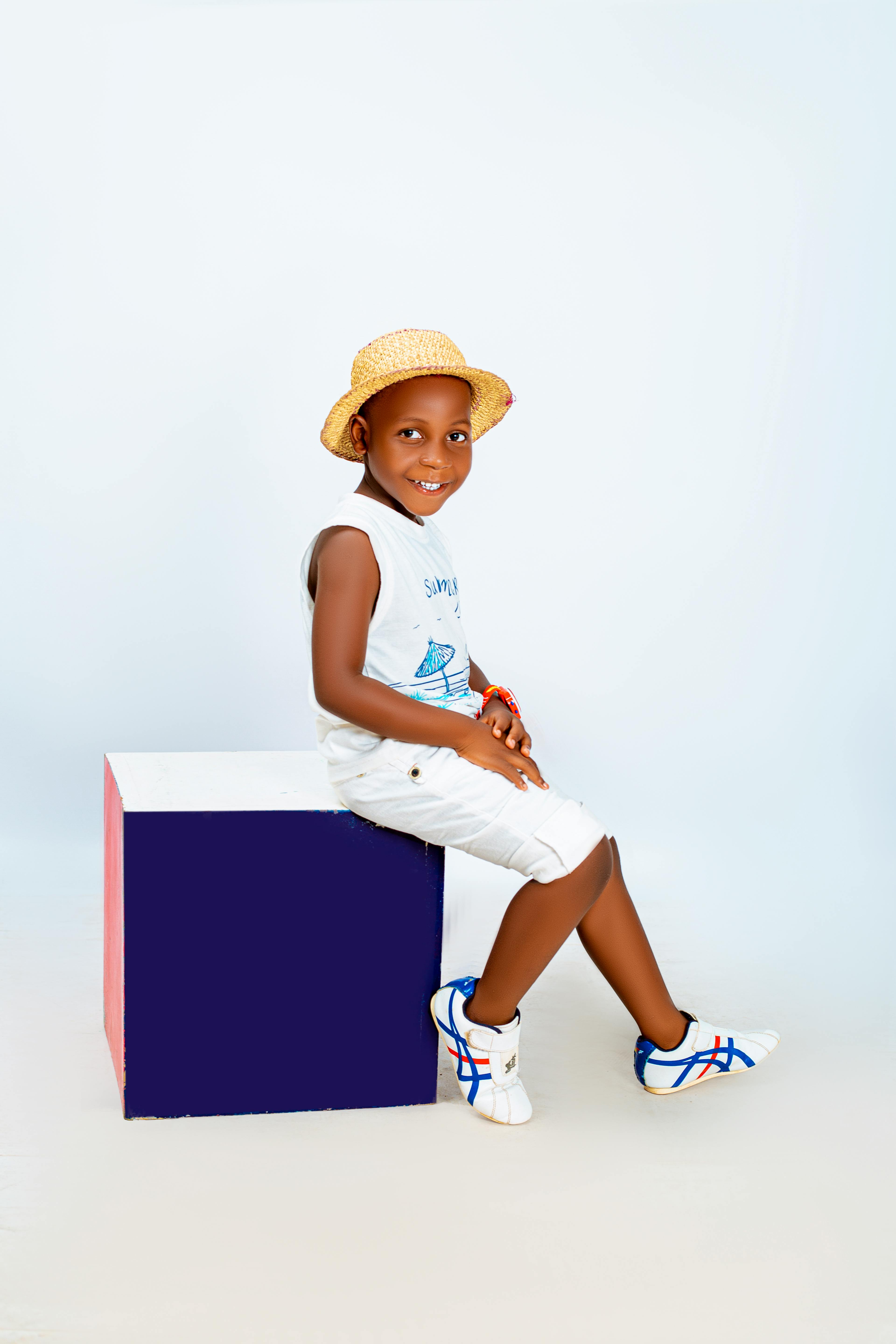Young boy in summer attire sitting on a colorful cube, exuding joy and style.