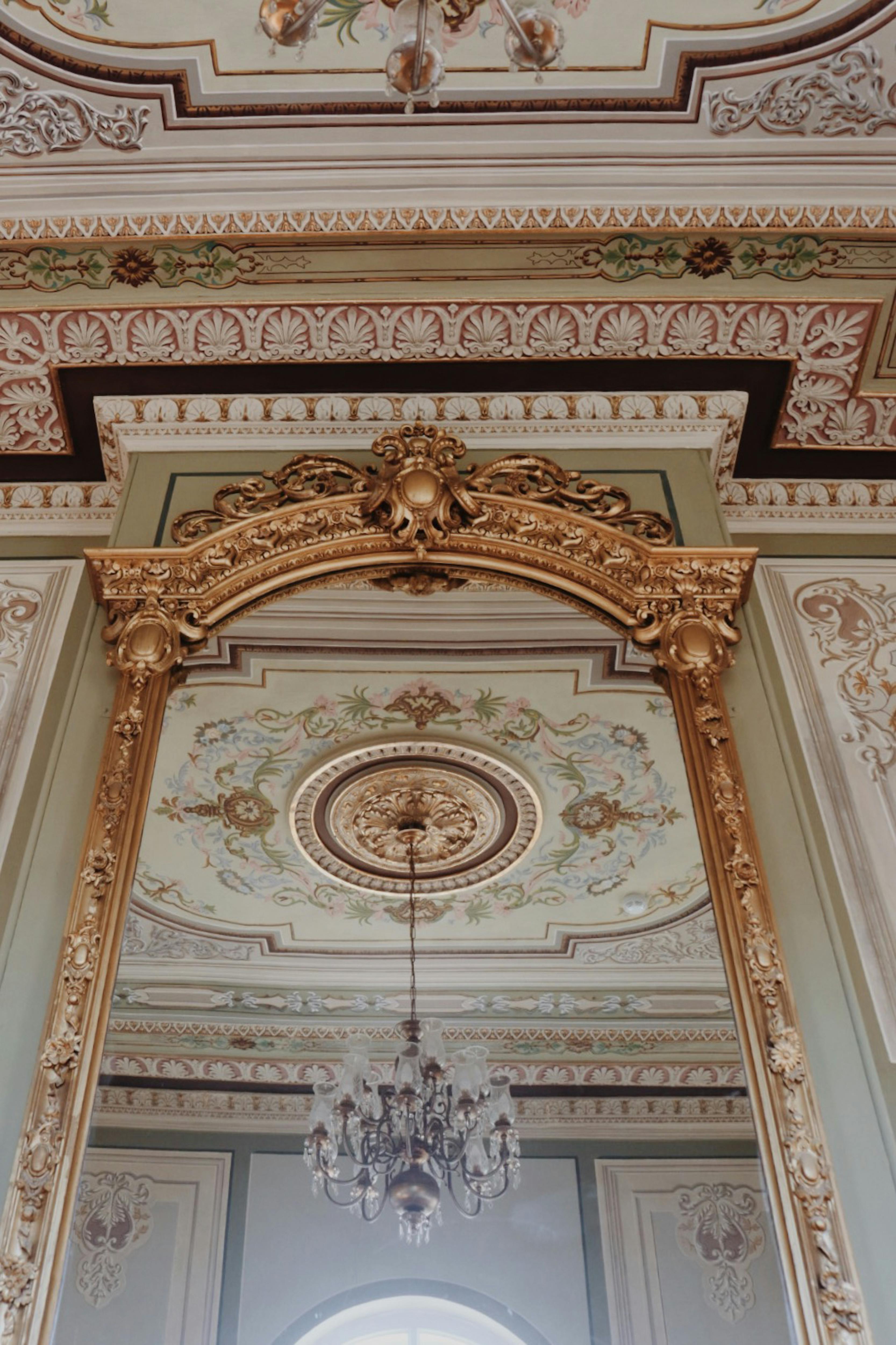 Gratuit Un intérieur luxueux avec un plafond orné et un miroir encadré doré reflétant un décor détaillé. Photos