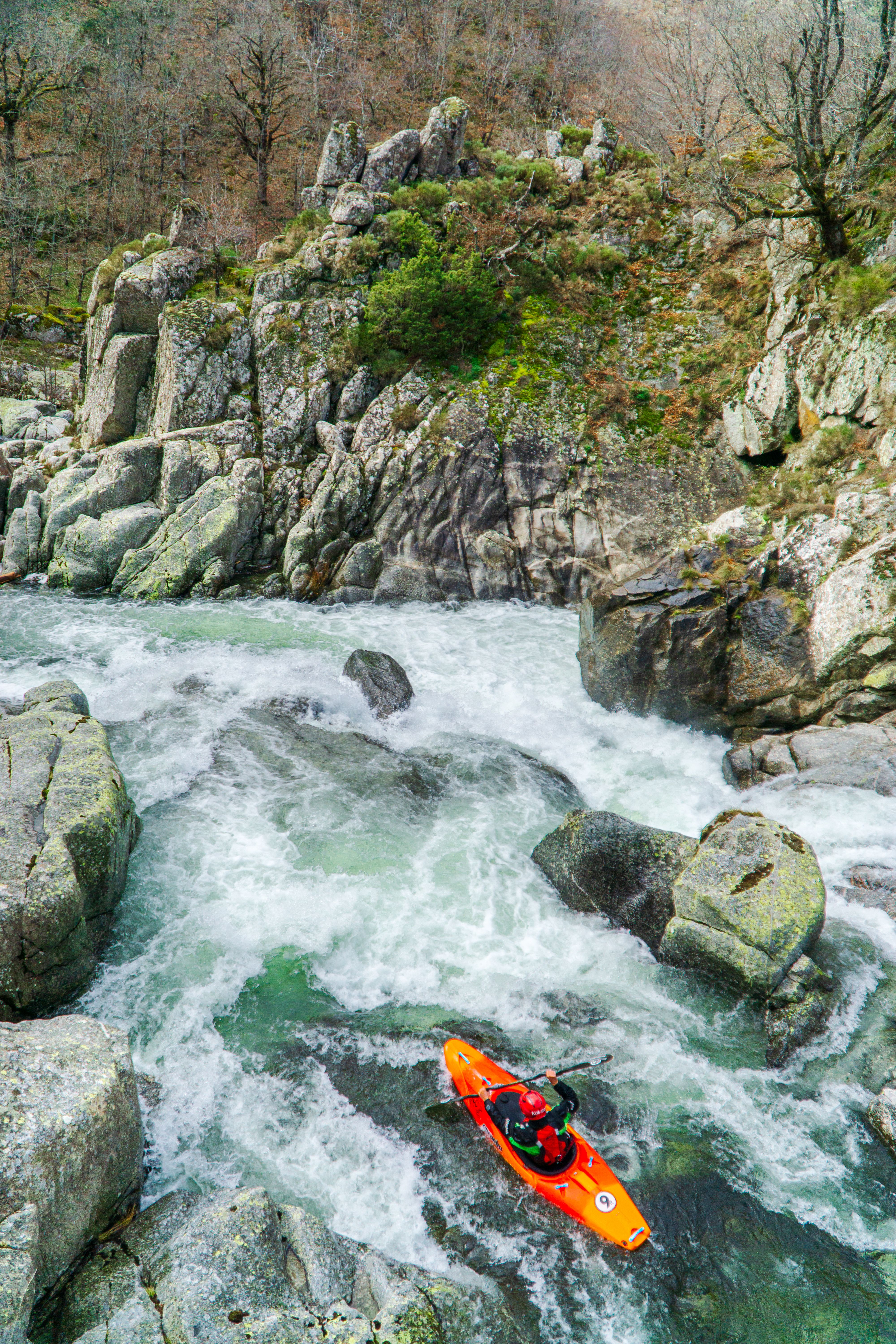 An adventurous kayaker skillfully navigates the whitewater rapids in Occitanie's rocky landscape.
