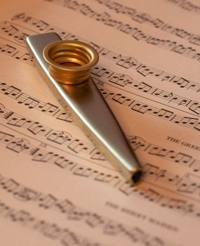 A brass kazoo elegantly placed on music sheet, creating a musical ambiance.