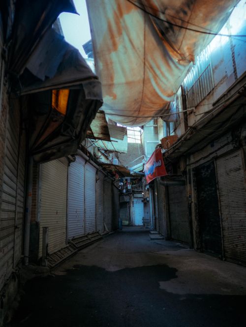 Free A deserted urban alleyway covered by a weathered tarp, evoking a sense of decay. Stock Photo