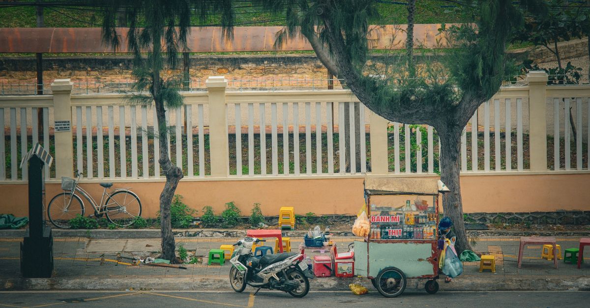 Traditional Vietnamese street food cart in Vũng Tàu cityscape setting.