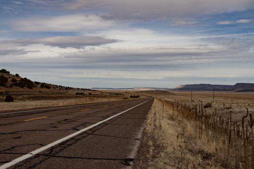 Free Desert road stretching into the horizon with dramatic sky and distant mountains. Stock Photo
