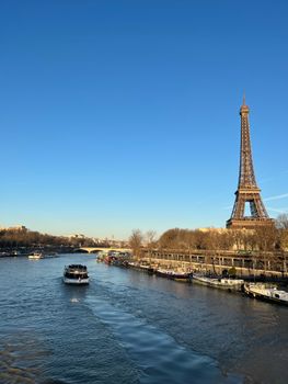 Stunning view of the Eiffel Tower and boats on the Seine River in Paris, France under a clear blue sky.