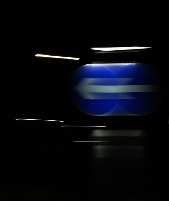Artistic blur of a blue road sign captured at night, creating a vivid abstract effect.
