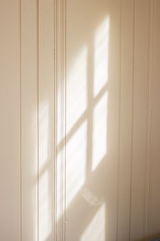 A minimalist image of sunlight casting window shadows on a wall, reflecting contemporary design.
