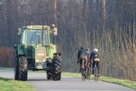 Cyclists alongside a tractor on a countryside road in Wetteren, Belgium.