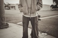 Sepia-toned image of a person in casual attire on a street corner.