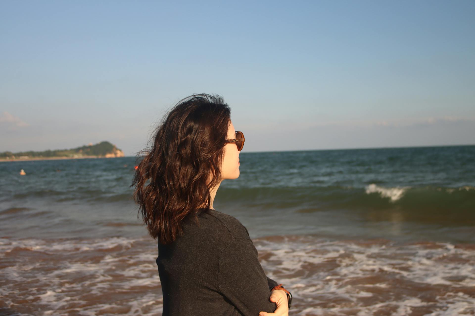 Young woman enjoying a serene moment at Qingdao beach, Shandong, China.