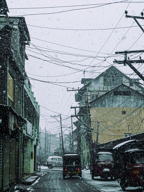 Free A busy urban street during a snowfall, capturing vehicles and buildings in a winter setting. Stock Photo