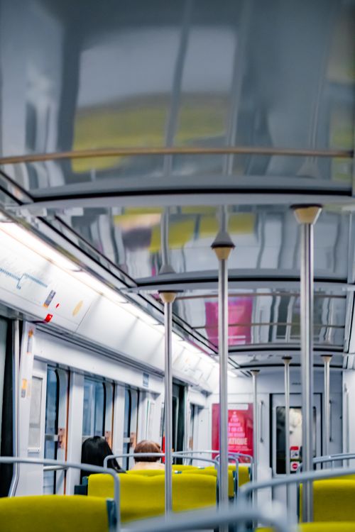 Free Interior of a Paris metro train showcasing empty seats and a couple of passengers, captured in soft light. Stock Photo