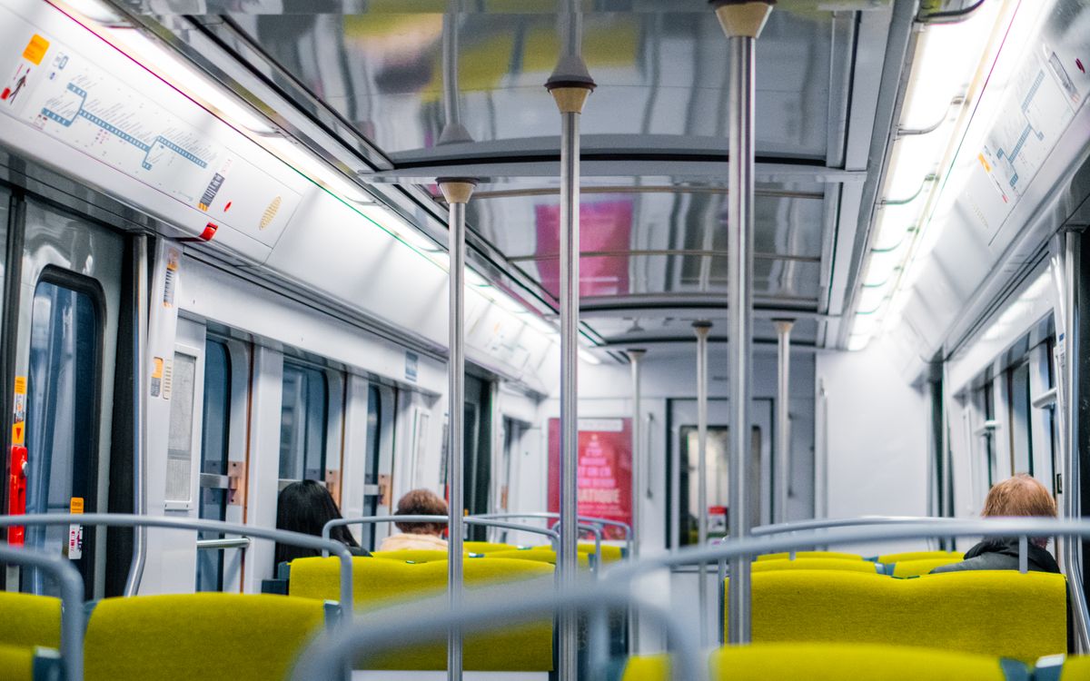 Interior view of a Paris metro train with passengers seated. Bright lighting and modern design.