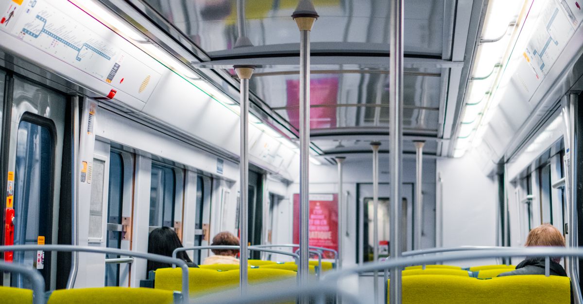 Interior view of a Paris metro train with passengers seated. Bright lighting and modern design.