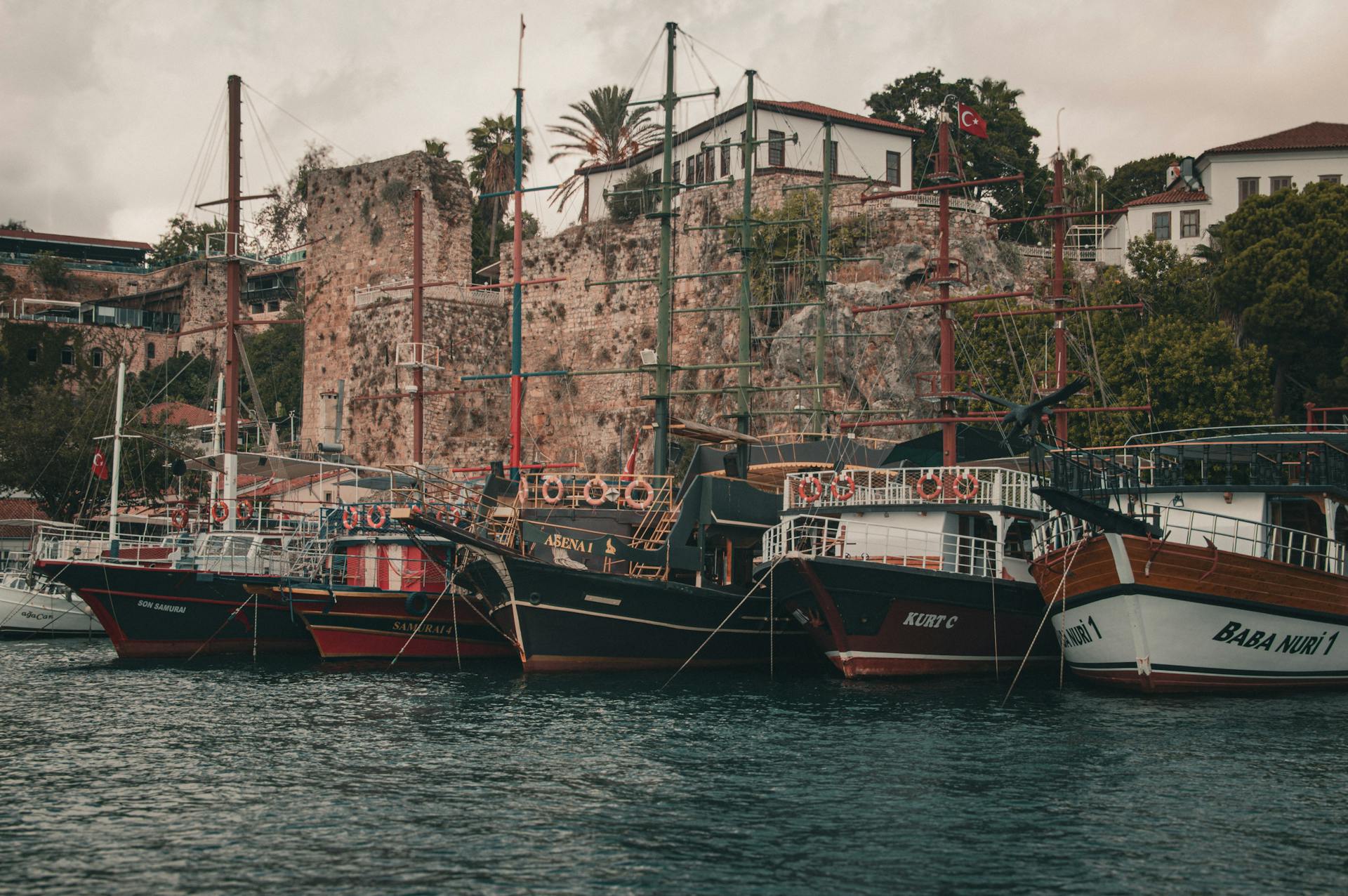 Scenic view of traditional Turkish ships docked in a historic harbor surrounded by ancient architecture.