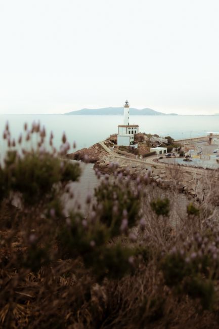 A stunning view of a white lighthouse along the Spanish coast with clear skies and scenic ocean backdrop.
