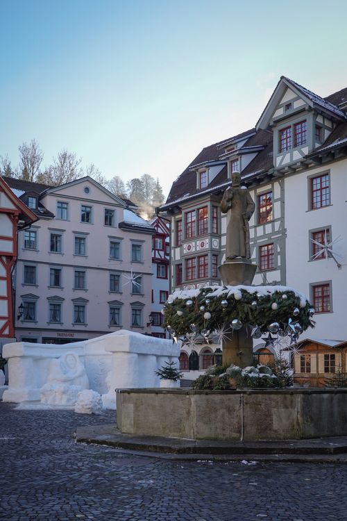 Free Serene Swiss town square featuring snow sculptures and historic architecture. Stock Photo