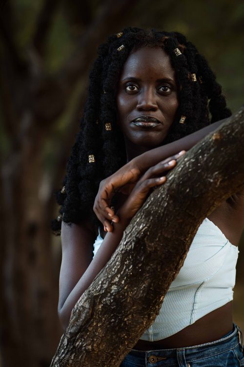 Free Striking portrait of a woman leaning on a tree outdoors, capturing a serene and contemplative moment. Stock Photo