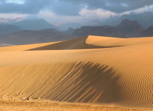 Free Serene desert landscape of Maspalomas dunes under cloudy sky. Stock Photo