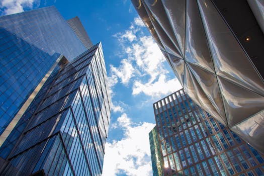 A low angle view of modern skyscrapers with glass facades against a clear blue sky in New York City.