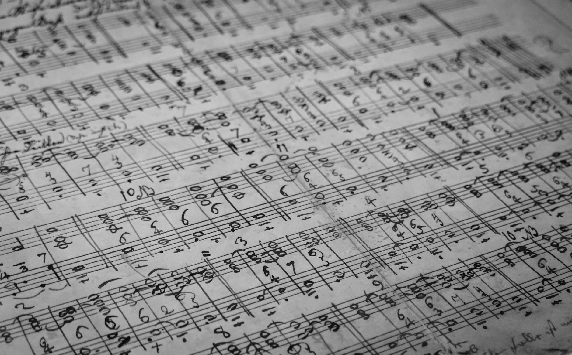 Detailed black and white photo of handwritten music sheets with notes and symbols.