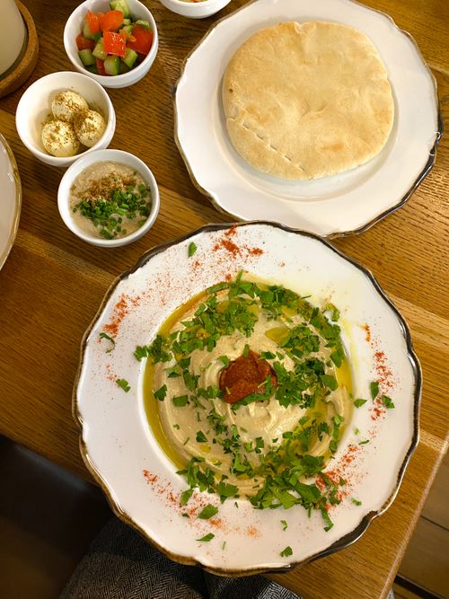 Free Delicious hummus garnished with herbs and spices, served with fresh pita bread and salads. Stock Photo