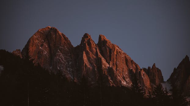 A dramatic view of a mountain range in Trentino-Alto Adige, Italy during dusk, capturing the serene winter beauty.