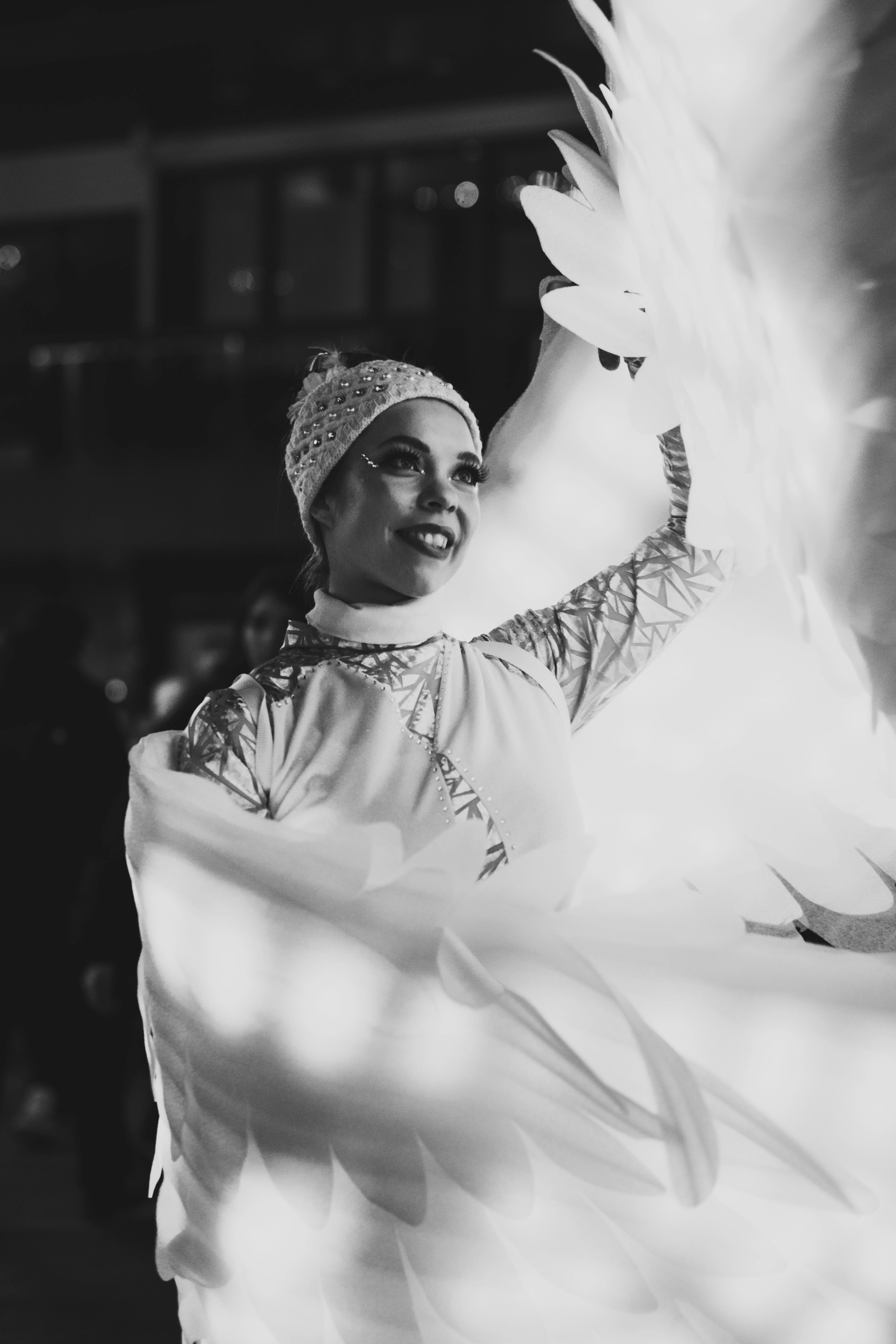 Ücretsiz Gülümseyen bir sanatçının süslü kanatlar takarak zarafet ve sanatçılığı çağrıştıran büyüleyici siyah beyaz görüntüsü. Stok Fotoğraflar